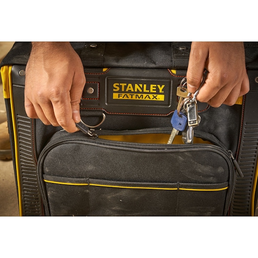 Photo of STANLEY FMST1-80148 Fatmax tool bag with hands attaching keys to the front key ring, close-up view.