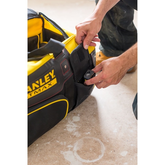 Photo of STANLEY FMST82706-1 tool bag with yellow interior, showing hand placing item in black side pocket.