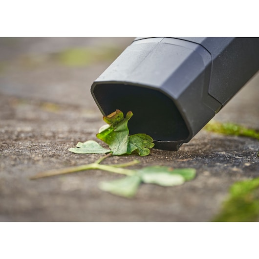 STANLEY SFMCBL714B-XJ blower nozzle clearing leaves on pavement, close-up photo.