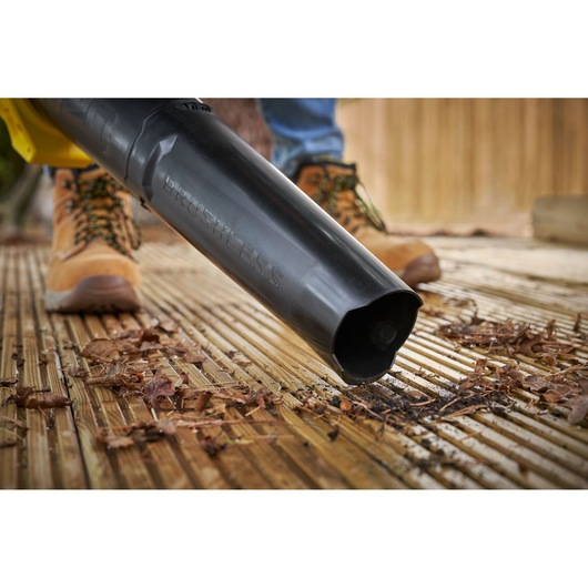 STANLEY SFMCBL730M1 leaf blower in action on wooden deck, close-up of nozzle clearing leaves.