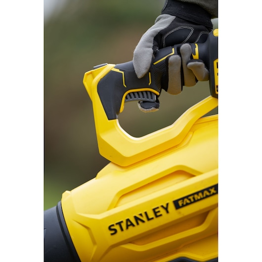 Stanley SFMCBL7M1 blower close-up showing yellow and black handle and Fatmax branding in outdoor setting.