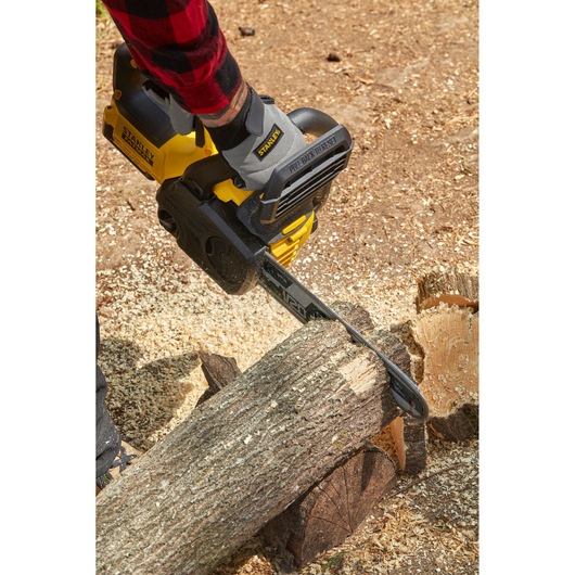 STANLEY SFMCCS630B cordless chainsaw cutting a log, shown in use outdoors.