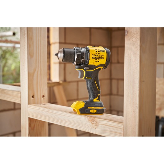 STANLEY SFMCD714D2T cordless drill driver in yellow and black, side view, placed on wooden frame.