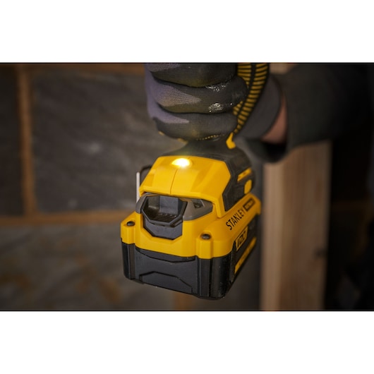 STANLEY SFMCD714D2T cordless drill close-up with LED light on, yellow and black design, in use indoors.