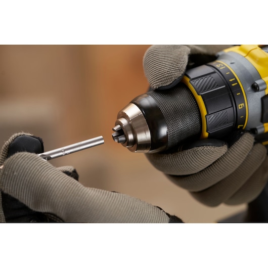 STANLEY SFMCD720D2K drill held in gloved hands, inserting a drill bit, product close-up angle.