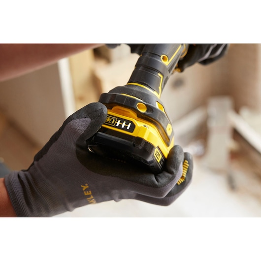 Photo of STANLEY SFMCD720D2K cordless drill being held by a gloved hand, focus on battery indicator.