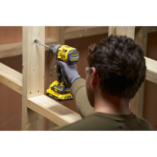 Photography of STANLEY SFMCD725B cordless drill in use drilling wood.