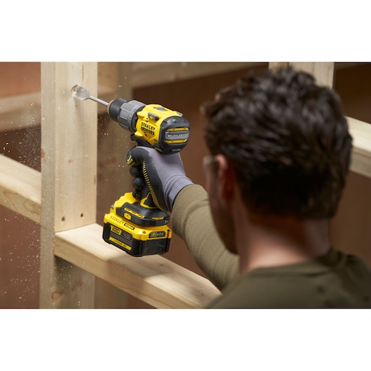 Photo of a person using a STANLEY SFMCD726B cordless drill to bore a hole in a wooden frame.
