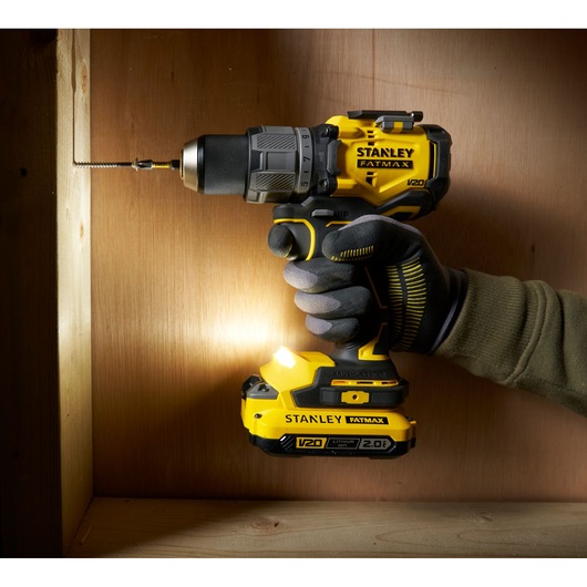 STANLEY SFMCD726B cordless drill in use drilling into wood, side angle, yellow and black design.