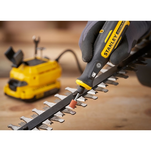 STANLEY SFMCE030B rotary tool used to grind metal blade, close-up angle, yellow and black design.