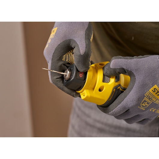 STANLEY SFMCE200B rotary tool held in gloved hands, close-up, yellow and black finish.