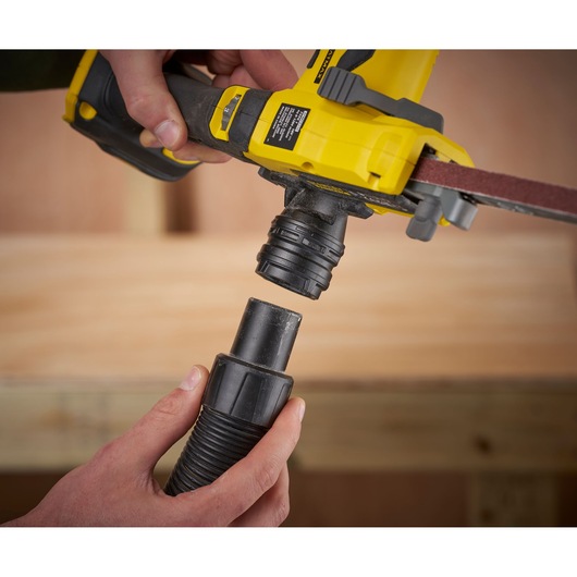 STANLEY SFMCE210B belt sander side view connecting to dust extraction hose, close-up.