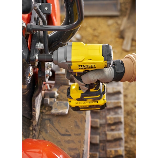 STANLEY SFMCF920B impact wrench in use, side angle, yellow and black, tightening bolt on machinery.