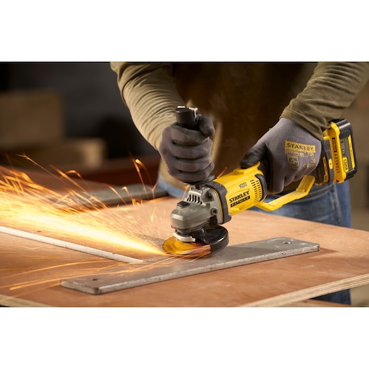 STANLEY SFMCG300B cordless angle grinder in use, grinding metal with sparks, close-up action shot.
