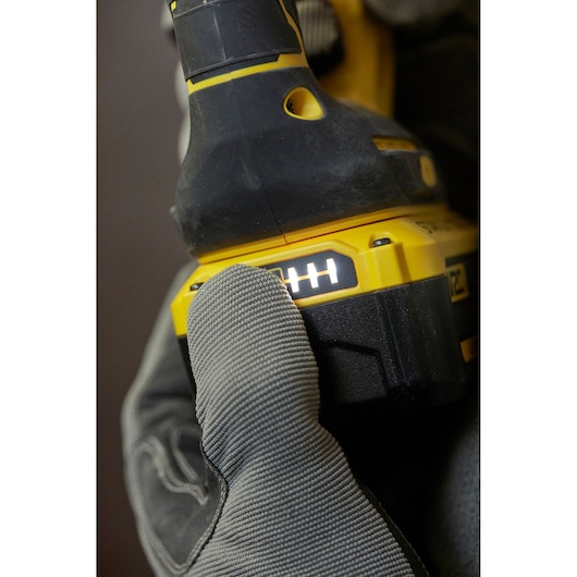 STANLEY SFMCH900M22 cordless drill power indicator close-up held by gloved hand, side angle.