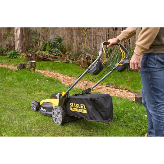 STANLEY SFMCMWS251M lawn mower in use, yellow and black, rear angle, on grass lawn.