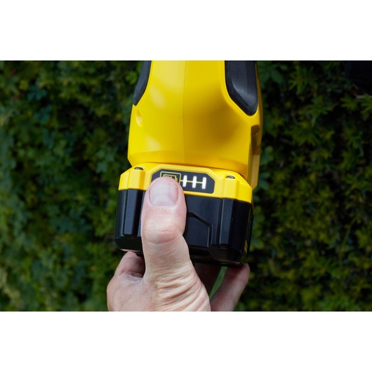 Photo of a STANLEY SFMCPH845B power tool battery pack held in hand outdoors.