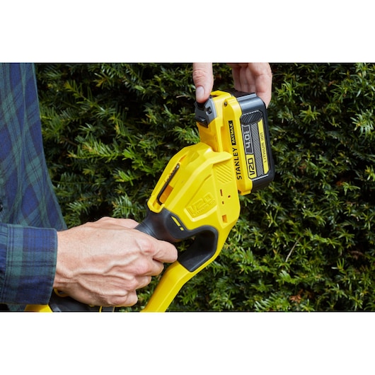 STANLEY SFMCPH845B battery installation on yellow outdoor power tool, close-up photography.