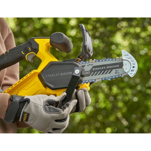 STANLEY SFMCPS415D1 chainsaw close-up in use, yellow and black body, FATMAX branding, outdoor background.