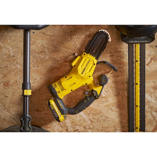 STANLEY SFMCPS415D1 yellow cordless pruner top view on plywood surface.