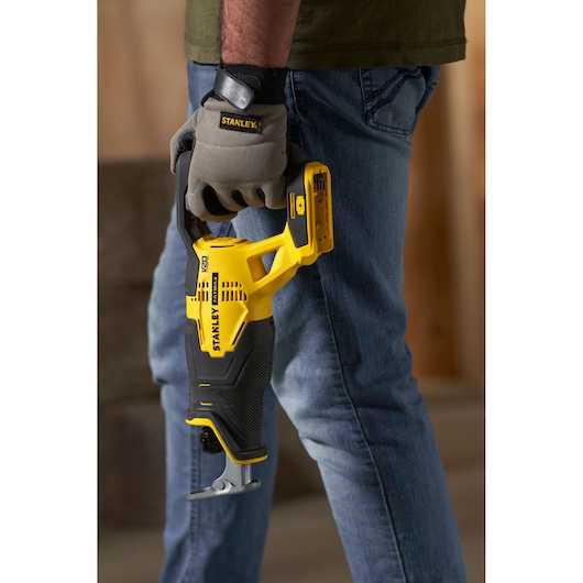 STANLEY SFMCS300B reciprocating saw held by worker in gloves, yellow and black, product side view.