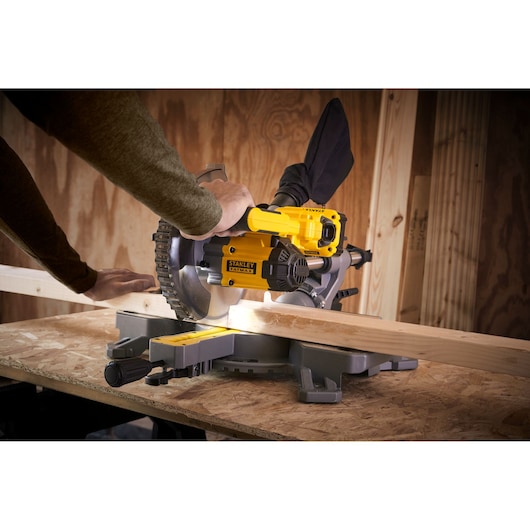 STANLEY SFMCS701M1 miter saw in use cutting wood, workshop setting, side angle.