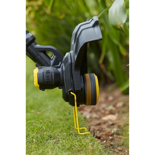 STANLEY SFMCST933M1 grass trimmer head close-up, showing yellow line guide on lawn edge.