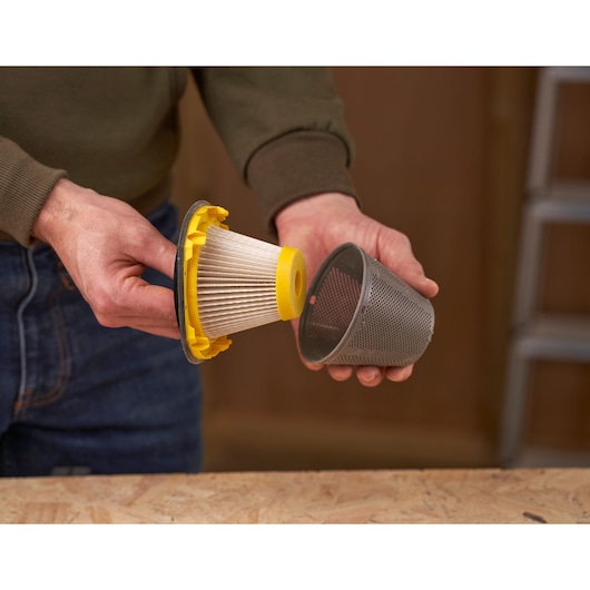 Stanley SFMCVH001B vacuum filter and mesh cover held by hand on workbench.