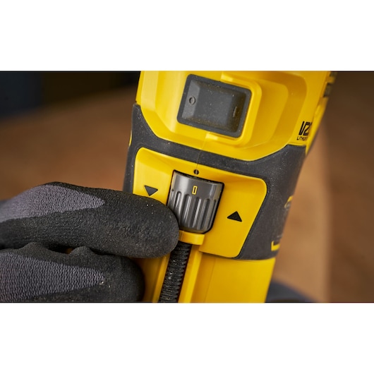 STANLEY SFMCW400B detail view of speed control switch on yellow power tool held by gloved hand.