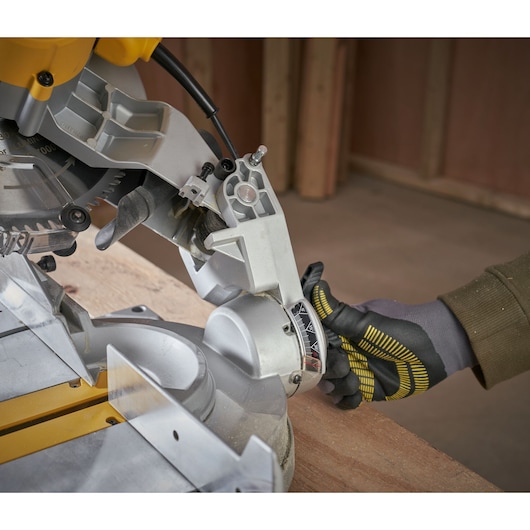 STANLEY SM1650 miter saw photography, close-up angle showing adjustment knob and gloved hand.