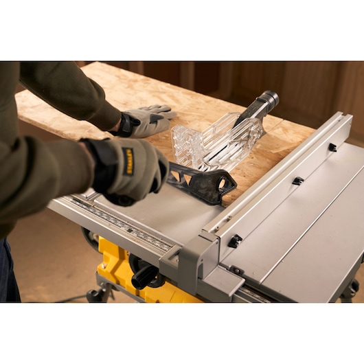 STANLEY SST1800 table saw close-up with gloved hands guiding wood and using safety push stick.