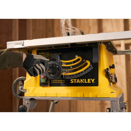 Photo of STANLEY SST1800 table saw, yellow base, control panel, side angle, glove adjusting knob.