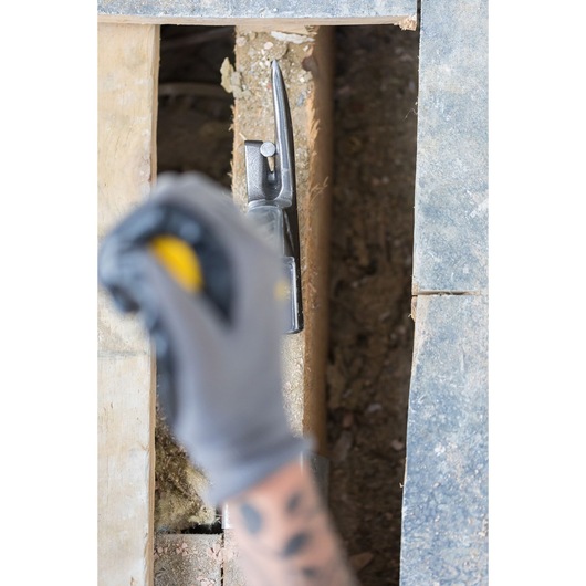 STANLEY STHT0-51312 claw hammer in use on wood during construction, partial view with gloved hand.