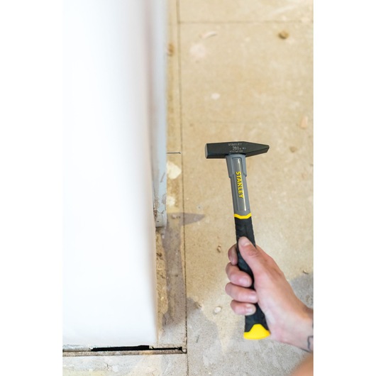 STANLEY STHT0-51906 hammer with black and yellow handle held in hand, indoor construction setting.