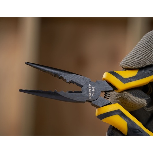 Photo of STANLEY STHT0-74363 pliers with black jaws and yellow-black handles in a gloved hand, close-up.