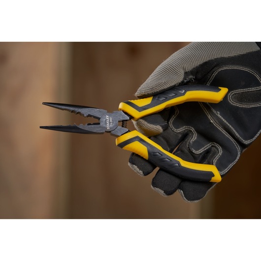 Photo of STANLEY STHT0-74363 pliers with yellow and black handles held by a gloved hand.
