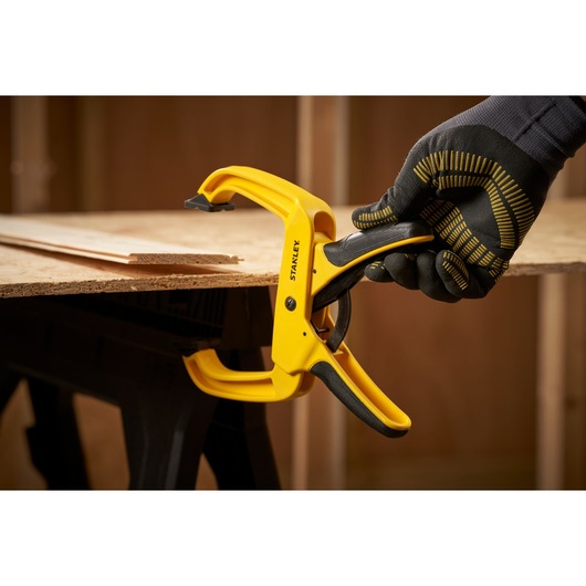 STANLEY STHT0-83200 quick-grip clamp in use, yellow and black, woodworking context, side angle