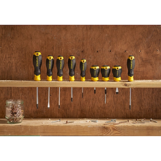 STANLEY STHT16181-0 screwdriver set with black and yellow handles on a wooden shelf, workshop setting.