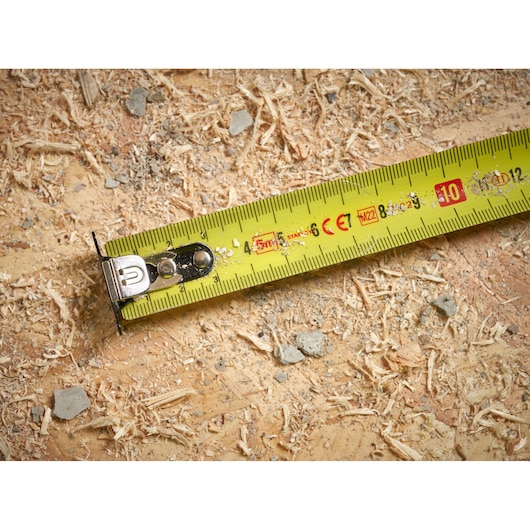STANLEY STHT37231-0 yellow measuring tape close-up on wood surface with sawdust and debris.