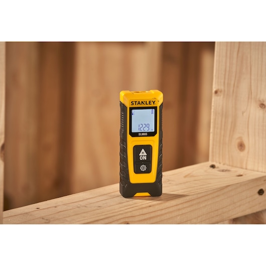 STANLEY STHT77065-0 laser distance measurer with digital display on wooden beam, photography category.