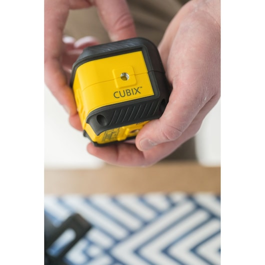 Photo of STANLEY STHT77498-1 CUBIX yellow and black laser level held in hand, product photography.