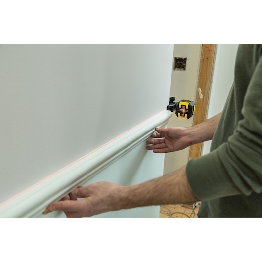 STANLEY STHT77498-1 laser level projecting line on wall during molding installation.