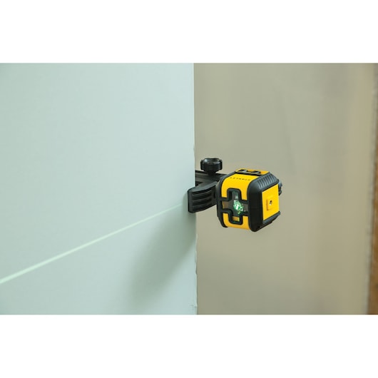STANLEY STHT77499-1 laser level tool mounted on wall, projecting green laser line, side angle photography.