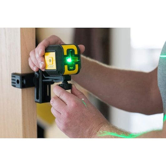 STANLEY STHT77499-1 laser level with green beam, mounted on wooden surface, close-up view.