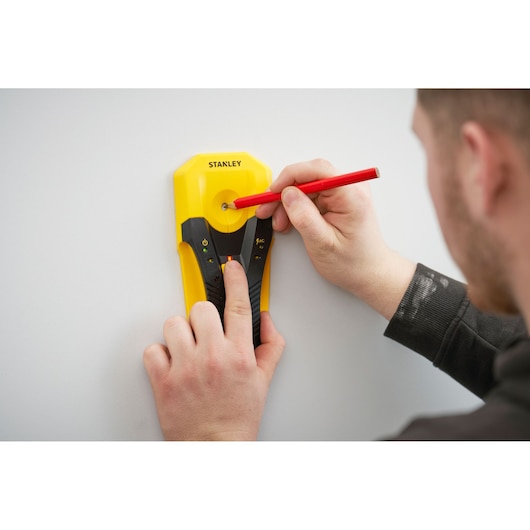 STANLEY STHT77588-0 stud finder used on wall with red pencil marking center, close-up photography.