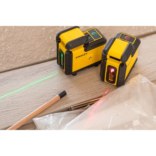 STANLEY STHT77640-1 laser level tools showing green and red laser lines on wood surface, pencil and screws nearby.