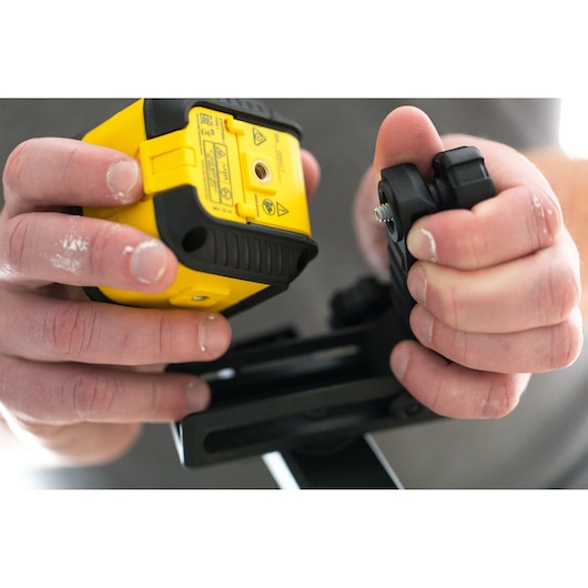 STANLEY STHT77649-1 laser level in yellow, being mounted on a black bracket, close-up photography.