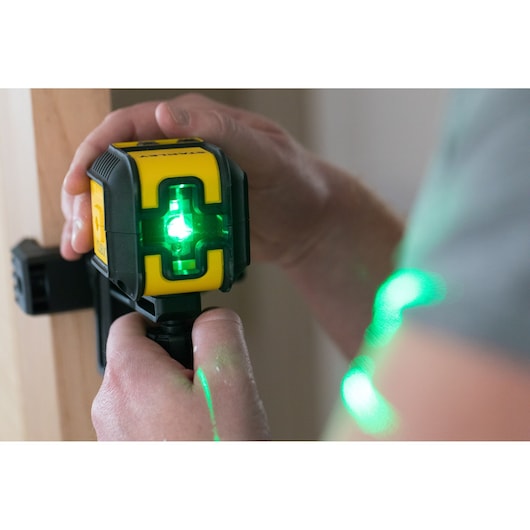 STANLEY STHT77649-1 green laser level in use, handheld near a wooden surface.