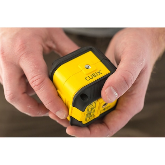 Photo of STANLEY STHT77649-1 Cubix yellow laser level held in hands, showing top and side details.