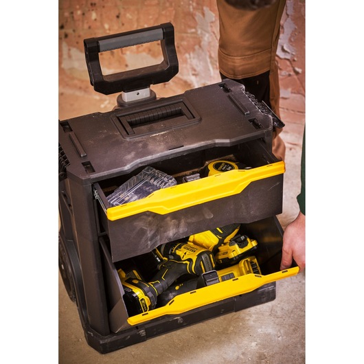 STANLEY STST1-79231 rolling tool chest with open yellow drawers containing power tools, front angle.